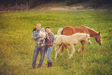 Happy family with a horse outdoors on green field in summer