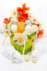 basket with easter eggs, flowers and white rabbits