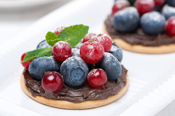 delicious mini cakes with chocolate cream and berries