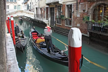Fotobehang Venetian gondolier in the gondola is transported tourists through canal waters of Venice Italy © smuki