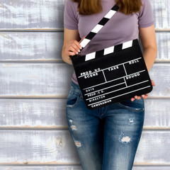 Young woman holding a clapboard against vintage background