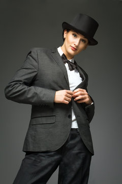 Young woman wearing man's suit posing over grey background