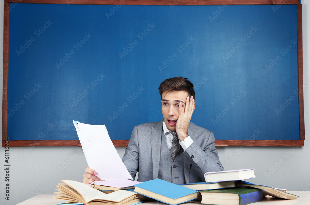 Wall mural young teacher sitting in school classroom