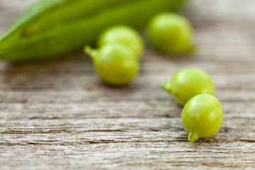 Peas and pea pods on an old wooden teak table.