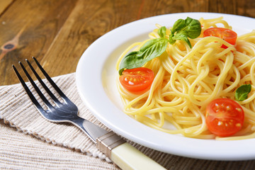Delicious spaghetti with tomatoes on plate on table close-up