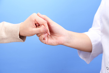 Medical doctor holding hand of patient, on light background