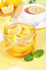 Tasty lemon jam with cup of tea on table close-up