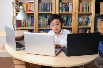 Intelligent school child working on multiple laptop computers