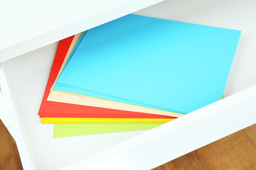 Colorful paper in open desk drawer close up