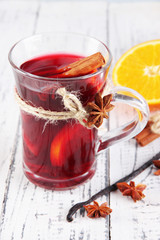 Mulled wine with oranges and spices on wooden background