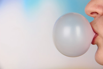 Person doing bubble with chewing gum on bright background