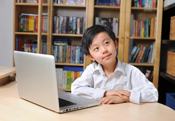 Happy Asian school boy in front of laptop computer