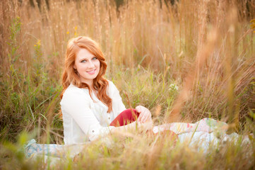 red haired girl in a field smiling