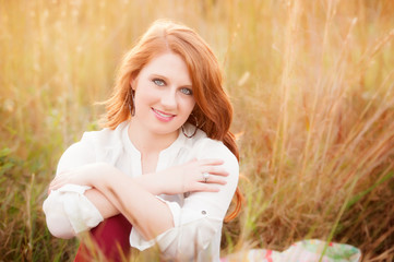 red haired girl in a field smiling