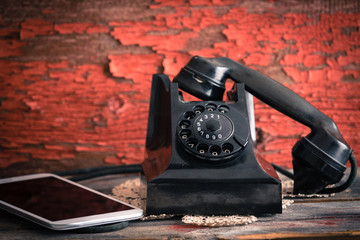 Old rotary telephone alongside a tablet computer