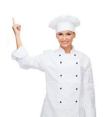 smiling female chef pointing finger to sonething