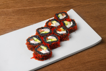 Image of black sushi with salmon on plate in restaurant