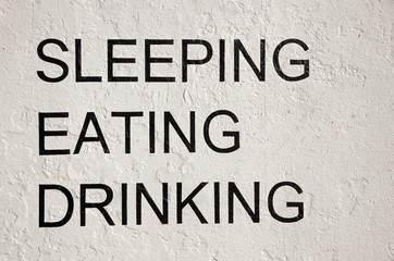 Sleeping eating drinking written on white wall