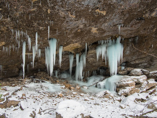 Group icicles hang down from a shelf in a cave