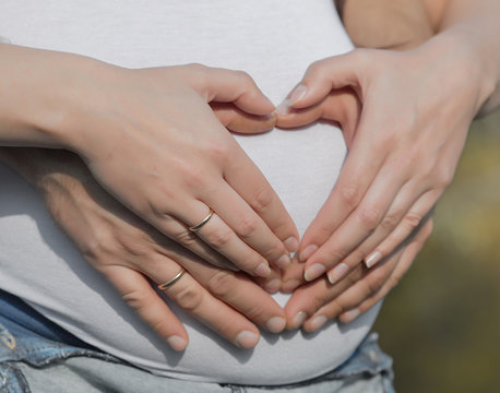Four hands on belly of expectant mother