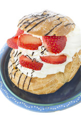 German Cream Puffs with strawberries in blue bowl, isolated