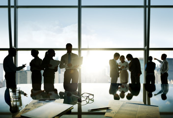 Group of business people discussing at sunrise reflected onto ta