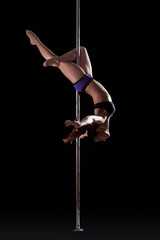 Athletic young pole dancer, isolated on black