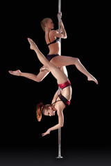 Two athletic young girls dancing on pilon