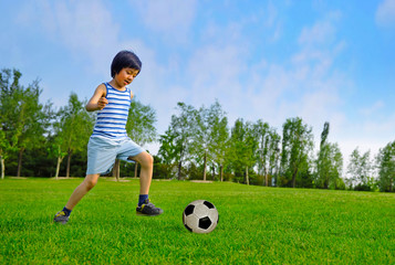 Young Asian boy playing soccer outdoors