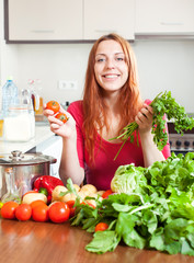 Girl with fresh vegetables and greens in kitchen