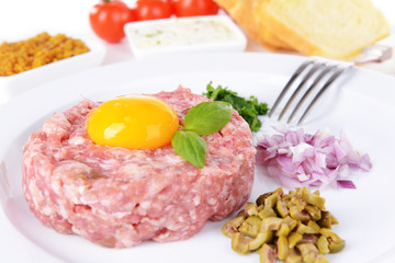 Delicious steak tartare with yolk on plate on table close-up