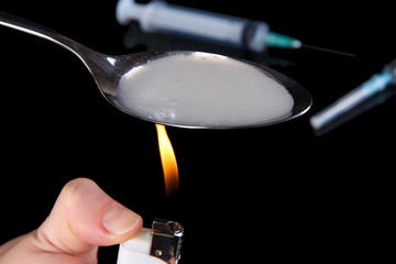 Heroin in spoon on black background