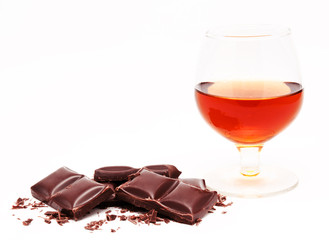 Glass with cognac and chocolate bars stack isolated on a white