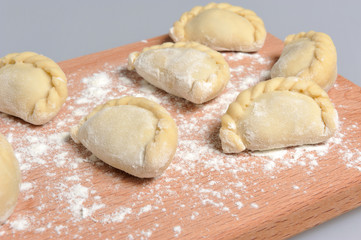 Uncooked floured pelmeni with a pattern on the cutting board on