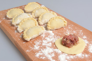 Uncooked floured pelmeni with a pattern on the cutting board on