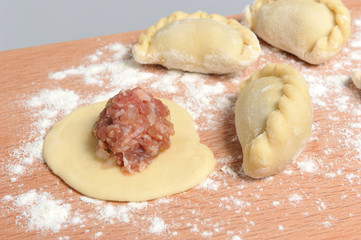 Uncooked floured pelmeni with a pattern on the cutting board on