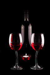 two glasses and a bottle of red vine with heart shaped candle