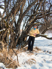Adult woman leaned against on a tree on snow background