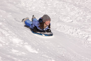 Girl sleds down hill.