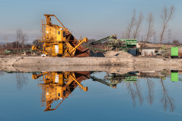 Kiesgrube mit Maschinen und einem Teich