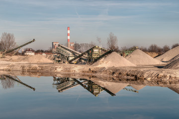 Kiesgrube mit Maschinen und einem Teich