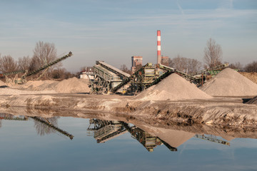 Kiesgrube mit Maschinen und einem Teich