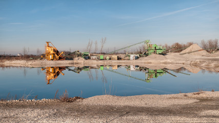 Kiesgrube mit Maschinen und einem Teich