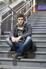 Handsome young man sitting on stairs