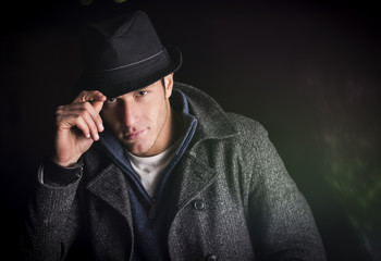 Young man at night, wearing winter coat and fedora hat - obrazy, fototapety, plakaty