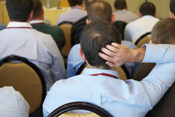 The audience listens  in a conference hall