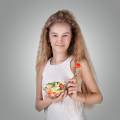 Girl eating vegetable salad, using fork - healthy food concept