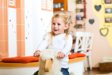 Mädchen schaukelt Schaukelpferd 