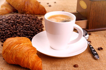 Coffee in white cup, grinder and croissant