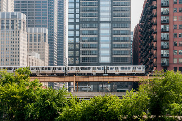 train on bridge with tall buildings in background - 61180377